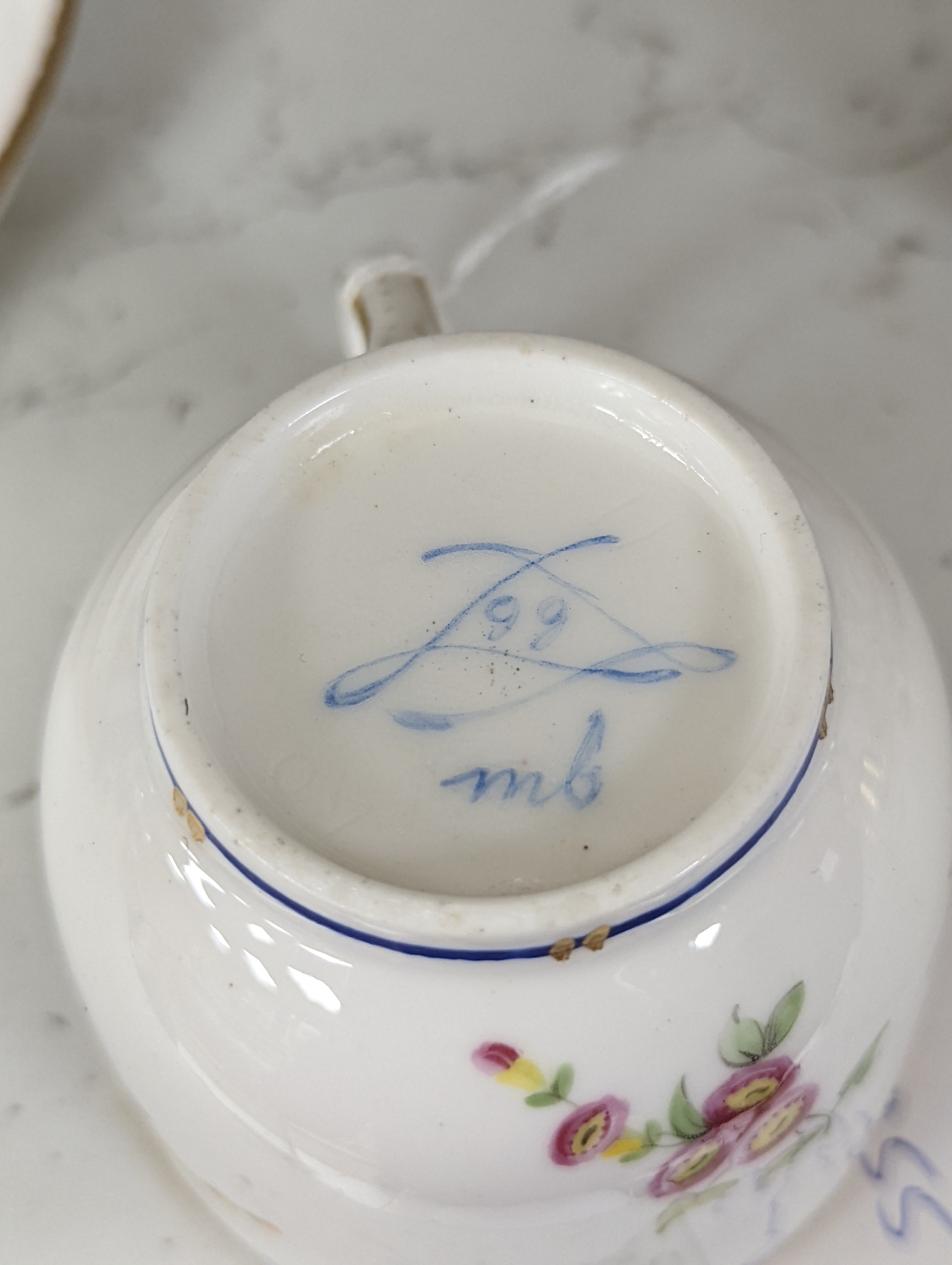 A Sevres coffee cup and saucer painted with floral bouquets under a dentil gilt and blue line border, date code 